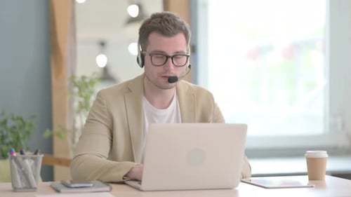 Young Businessman with Headset Looking toward Camera in Call Center