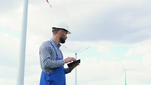 Engineer Checks Wind Turbine System with a Tablet Alternative Energy Wind Farm