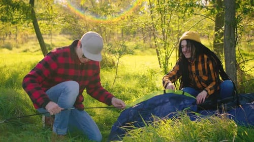 Couple Setting Up a Tent in Sunny Meadow