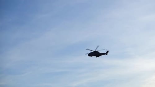 Silhouette of helicopter flying past.