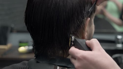 Using a Trimmer the Hairdresser Makes the Brunette's Hairstyle in the Temple Area More Neat and