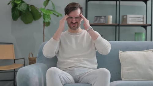 Adult Man Rubbing Temples on Sofa