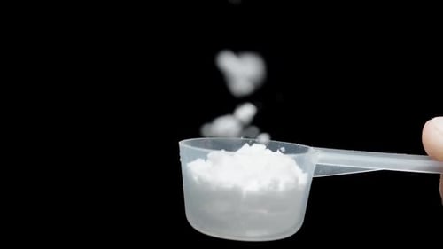 White powder from a measuring spoon, in slow motion, flies directly at you and fills the entire