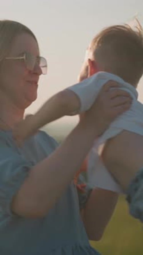 Happy Mother Spinning Child in Sunny Grassy Field with Joyful Play