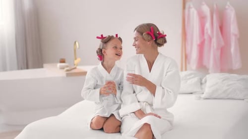 Mother and Daughter Enjoying a Relaxing Day at a Spa With Drinks and Hair Rollers