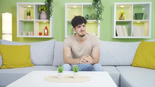 Young Man Exhibits Sadness Sitting on Couch