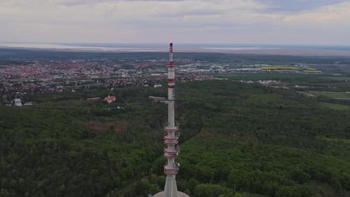 An aerial view of a tall telecommunication tower standing amidst a lush green forest. The background