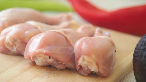 Raw Chicken Pieces on Cutting Board with Vegetables