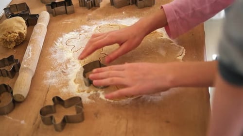 Child Cutting Christmas Cookie Shapes in Kitchen