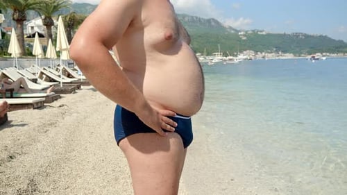 Man Standing on Sandy Beach on Sunny Day