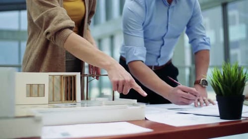 Midsection of Young Architects with Model of a House Standing in Office,