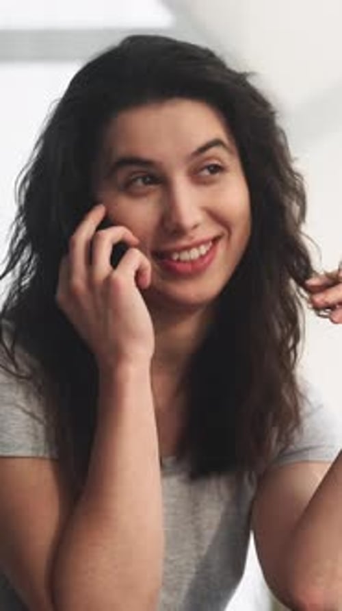 Smiling Brunette Woman Chatting on Mobile Phone Indoors
