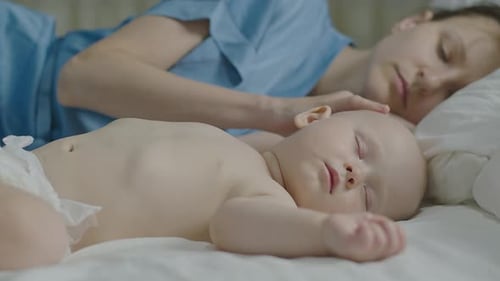 Sleeping Baby and Mom Resting in Bed