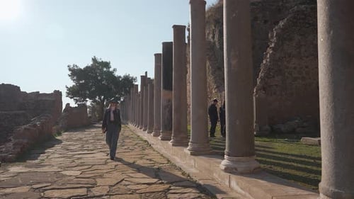 Young Woman Walking Among Ancient Ruins on Sunny Day
