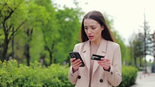 Woman Using Phone and Credit Card in City