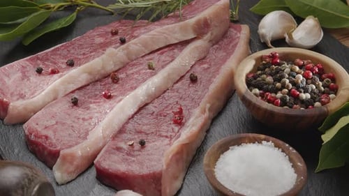 Three Raw Steaks with Pepper and Rosemary