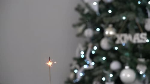 Sparkler Burning With Christmas Tree in Background