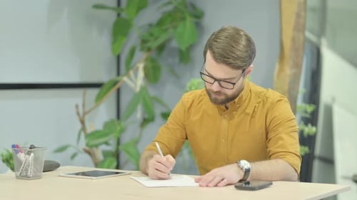 Young Man Writing Documents in Office