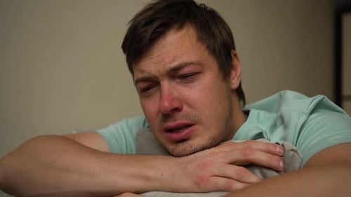 Young Man Expressing Deep Sorrow While Crying on a Pillow