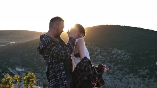 Man and Woman in Love are Having Fun and Dancing on a Cliff Overlooking the Sea at Sunset