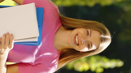 Vertical Screen Female Student with Books in Hands Standing in Park