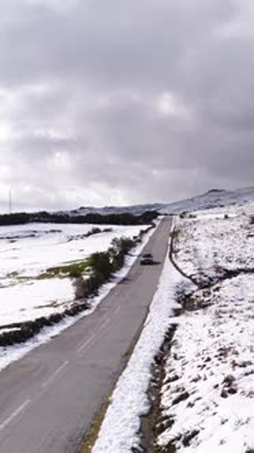 Vertikales Video einer Straße im Winter mit schneebedeckten Bergen