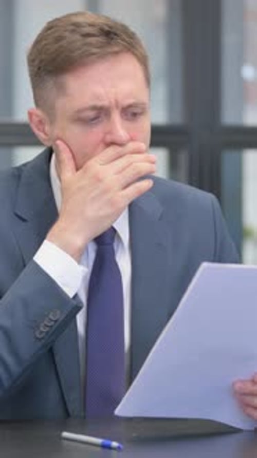 Worried Businessman Looks at Documents in Office Setting