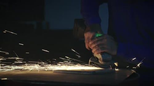 Sparks flying from angle grinder on metal in workshop