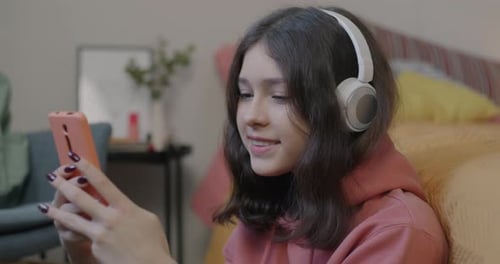 Girl with Headphones Using Smartphone Indoors at Home