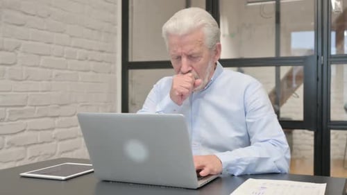 Coughing Senior Businessman Using Laptop in Office