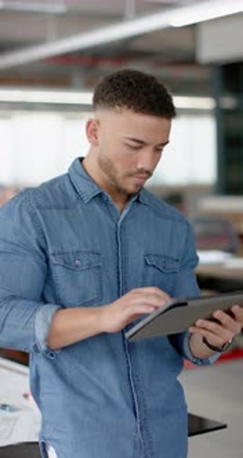 Vertical video of portrait of happy biracial businessman using digital tablet at office