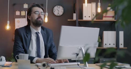 Loop of Tired Employee Stretching Arms and Back Feeling Exhausted Working Late in Office at Night