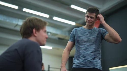 Lowangle View of Muscular Personal Instructor Explaining Technique of Exercise to Young Beginner