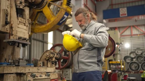 Senior experienced technician checking and maintenance a large machine in metal sheet factory