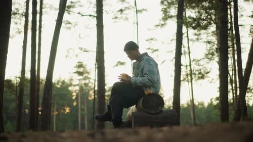 Man Relaxing Outdoors Drinking Coffee in a Forest