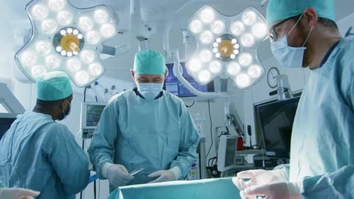 Gleitaufnahme eines vielfältigen Teams professioneller Chirurgen, die einen invasiven Eingriff an einem Patienten in t durchführen