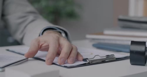 Man Reviews Documents, Writes Notes at Office Desk