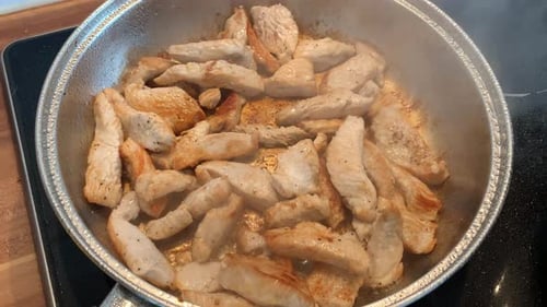 Sauté strips of meat in a pan on an electric stove