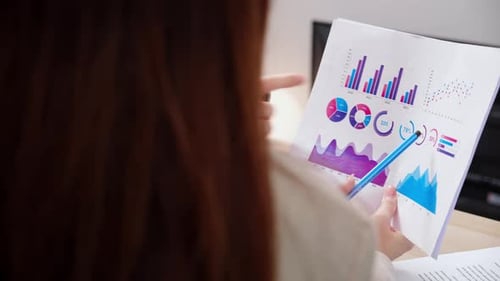 Nahaufnahme zweier Geschäftsfrauen, die Finanzgrafiken und -diagramme im modernen Büro überprüfen.