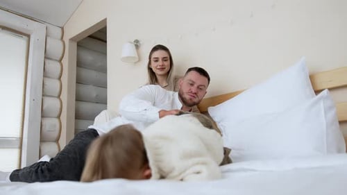 Happy family playing on bed in bright bedroom