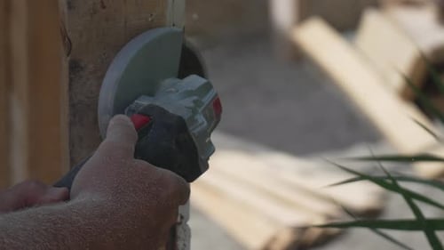 Hands Using Grinder to Cut Wood
