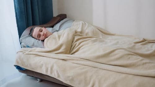 Man Sleeping Peacefully in Bed Under Blanket