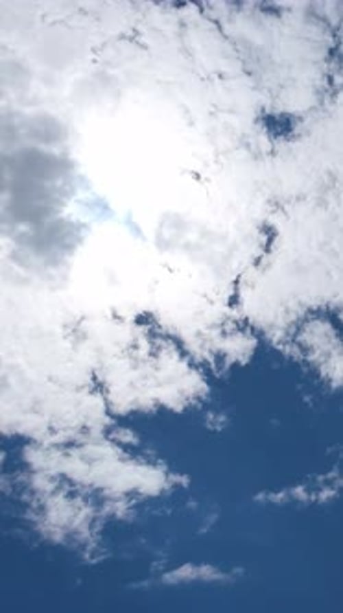 Weiße Wolken bewegen sich über die strahlende Sonne am blauen Himmel
