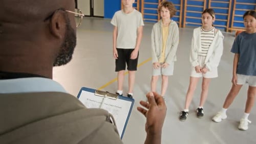 Teacher Discusses Lesson Plan with Children in Gym