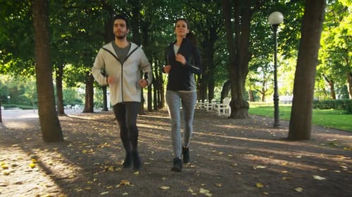 Young Woman and Man Running Together Forward Towards Camera in Bright Sunny Day