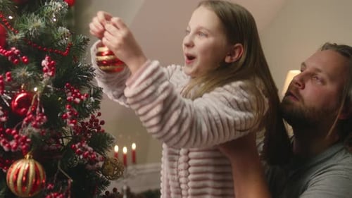 Father Lift His Daughter Up to Put Christmas Ball on Tree