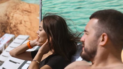 Young couple in a hotel relaxing on sunbeds and communicating