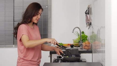 Woman Cooking Vegetables in Frying Pan at Home