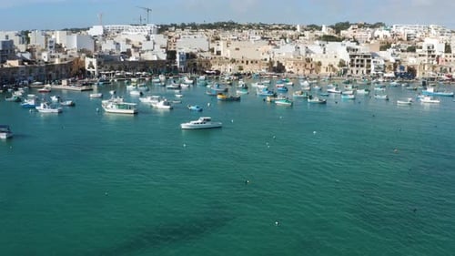 Colorful Boats In The Harbor Of Mediterranean Fishing Village Marsaxlokk, Malta - aerial drone shot