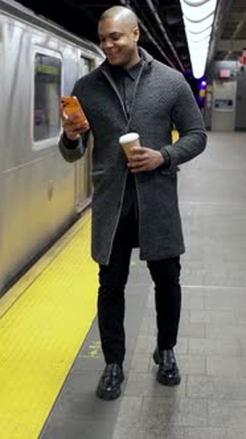 Stylish Businessman Using Smartphone and Drinking Coffee Waiting for the Subway